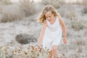 family photographer in Mallorca - little girl admiring the wild flowers at the beach