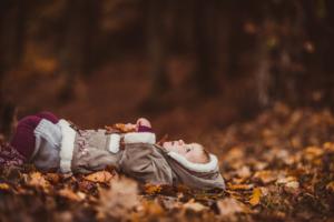 mallorca family lifestyle photography - a baby lying on autumn leaves and looking up at the sky