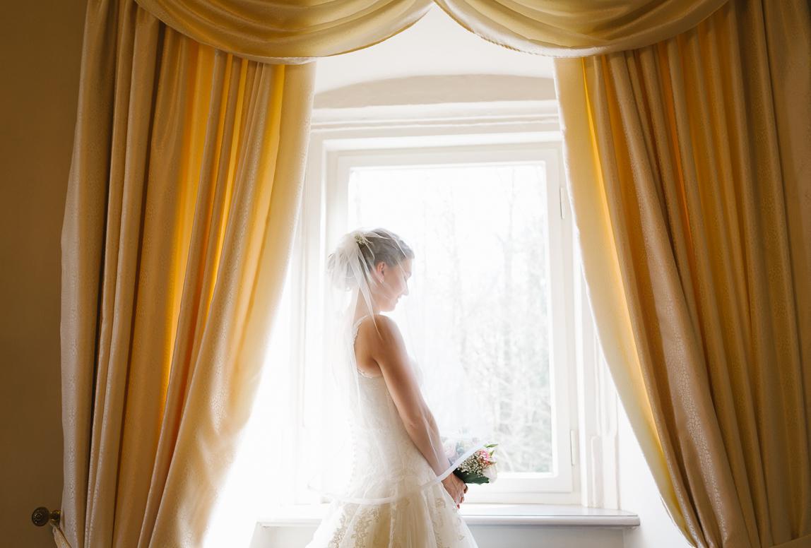 bride at the window before wedding - by Mallorca wedding photojournalist in mallorca romany flower - getting ready