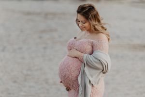 mallorca maternity photographer - a beautiful woman in a cute dress touching her baby bump