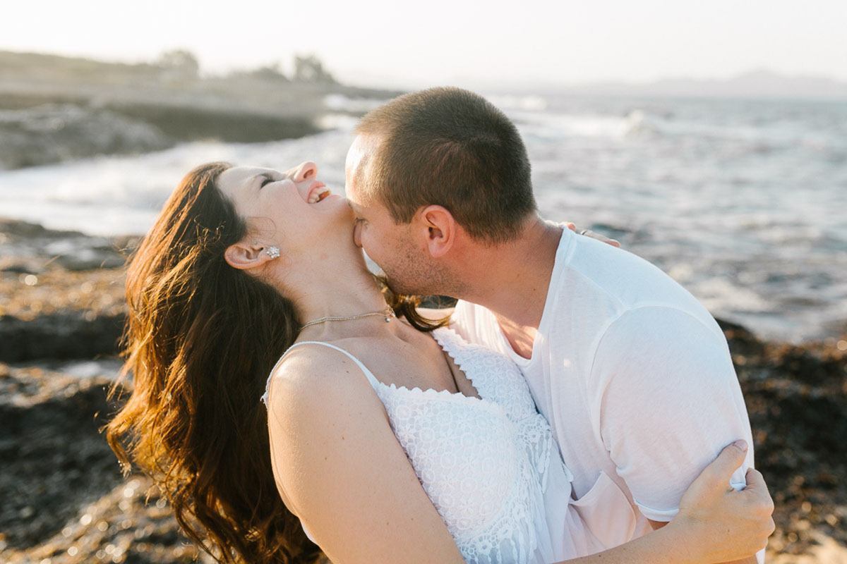 he kisses her neck engaged couples in white at their engagement photography session