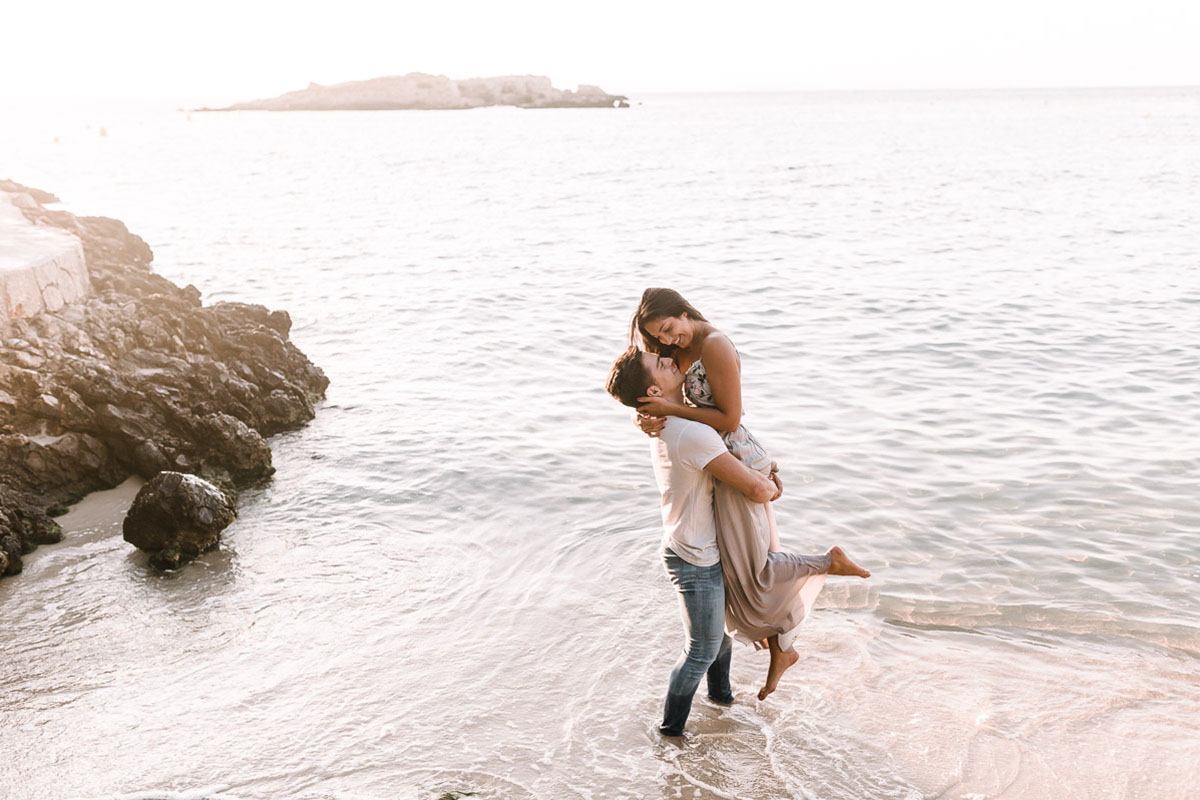 boyfriend lifting girlfriend by the beautiful beach of mallorca