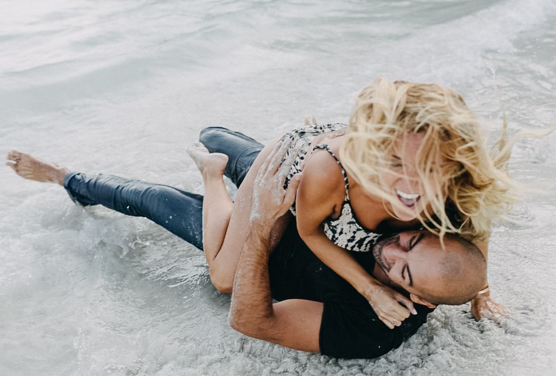 Modern couple photography in Mallorca - playful couple rolling at the sand