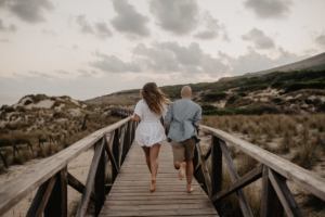 Mallorca elopement wedding photographer photographs couple running away on wooden planks in Cala Mesquida