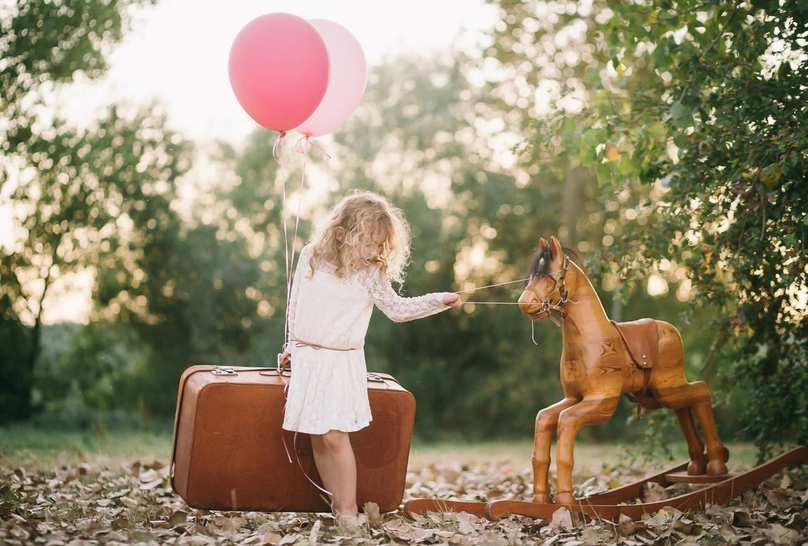 Mallorca Photographer for artistic Family pictures photographs girl with wooden horse and vintage suitcase