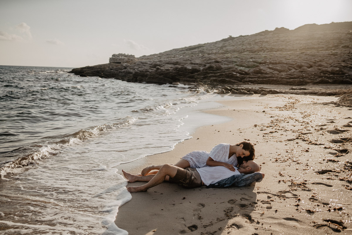 couple enjoying their mallorca honeymoon lying at the beach of cala mesquida during photo shoot with romany flower - best photographer in cala ratjada