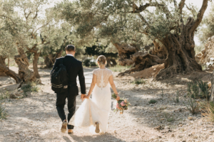 Adventure elopement spain: bride and groom walking through olive grove